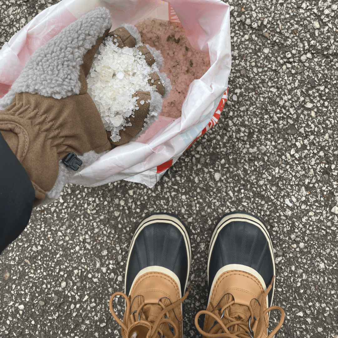 scooping salt with hand out of a 50# bag of safety salt sitting on driveway