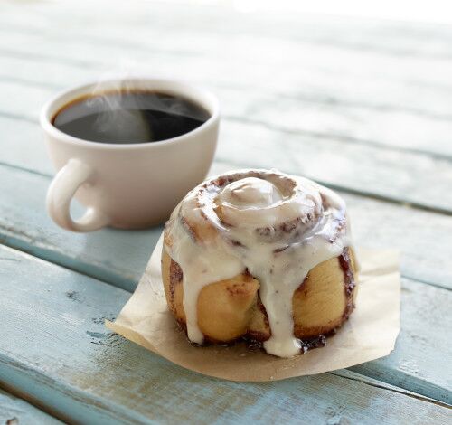 cinnabon cinnamon roll and cup of coffee on table