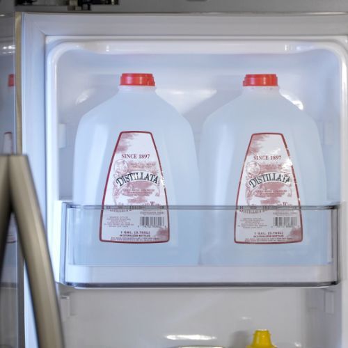 Distillata distilled 1 gallon water bottles on fridge shelf